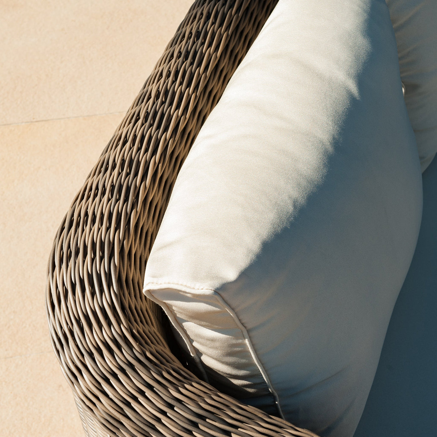 Fauteuil de jardin Calvi Meublot en rotin avec coussin beige, détails de l'assise et du cadre en extérieur.