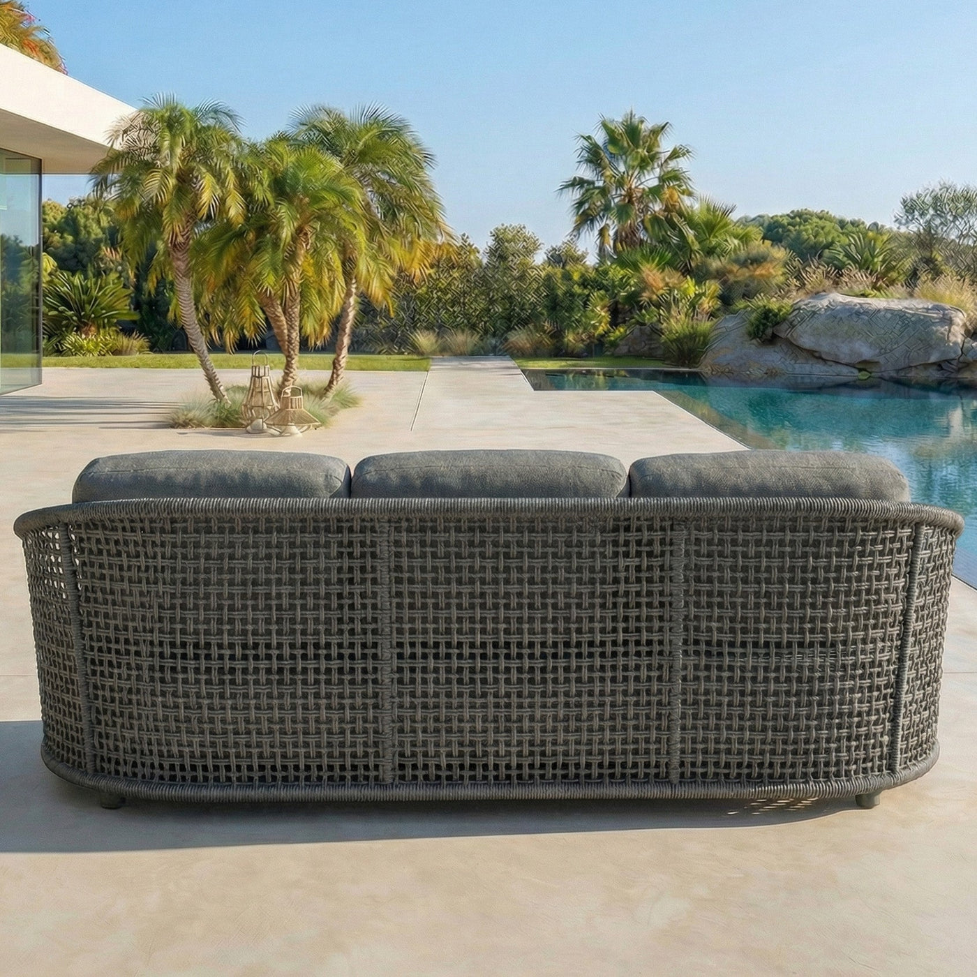 Canapé de jardin Riviera 5 places de la marque Meublot, avec coussins anthracite, dans un salon de jardin extérieur.