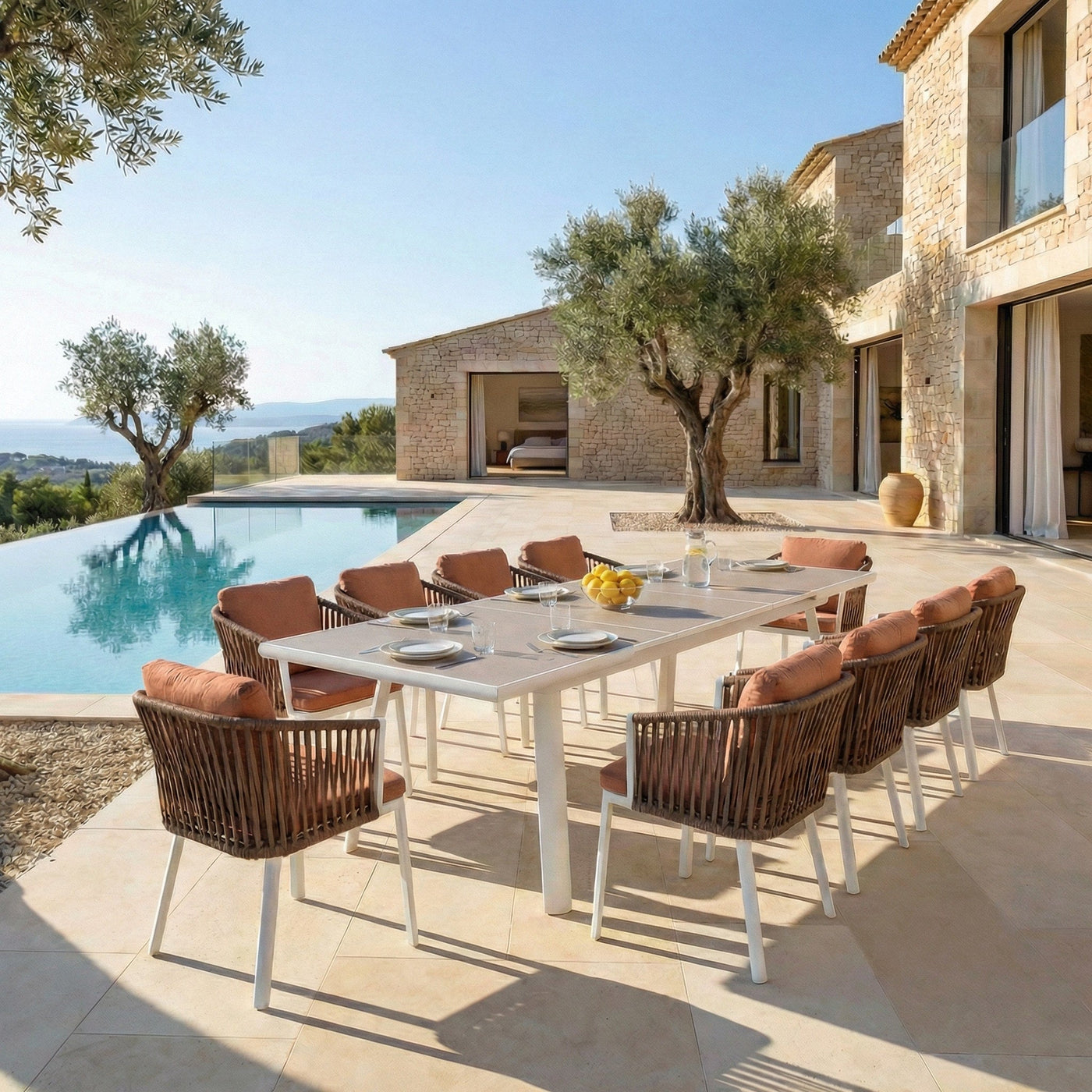 Table de jardin extensible automatique Amalfi en aluminium avec 12 places, gris clair, accompagnée de fauteuils terracotta.