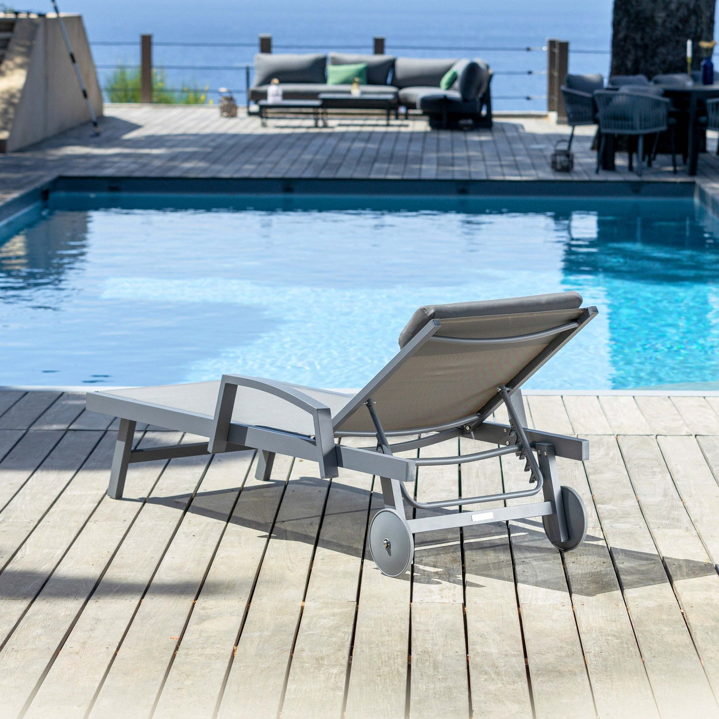 Transat Pirae gris avec repose-tête ajustable, design moderne pour bains de soleil, par Meublot, vue de derrière.