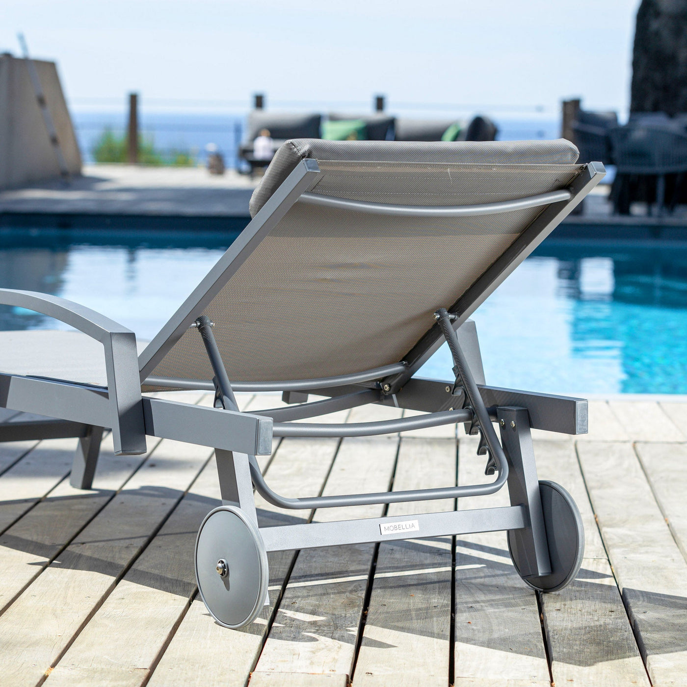 Transat Pirae gris avec coussin, bain de soleil moderne en bois et tissu confortable, idéal pour détente en extérieur.