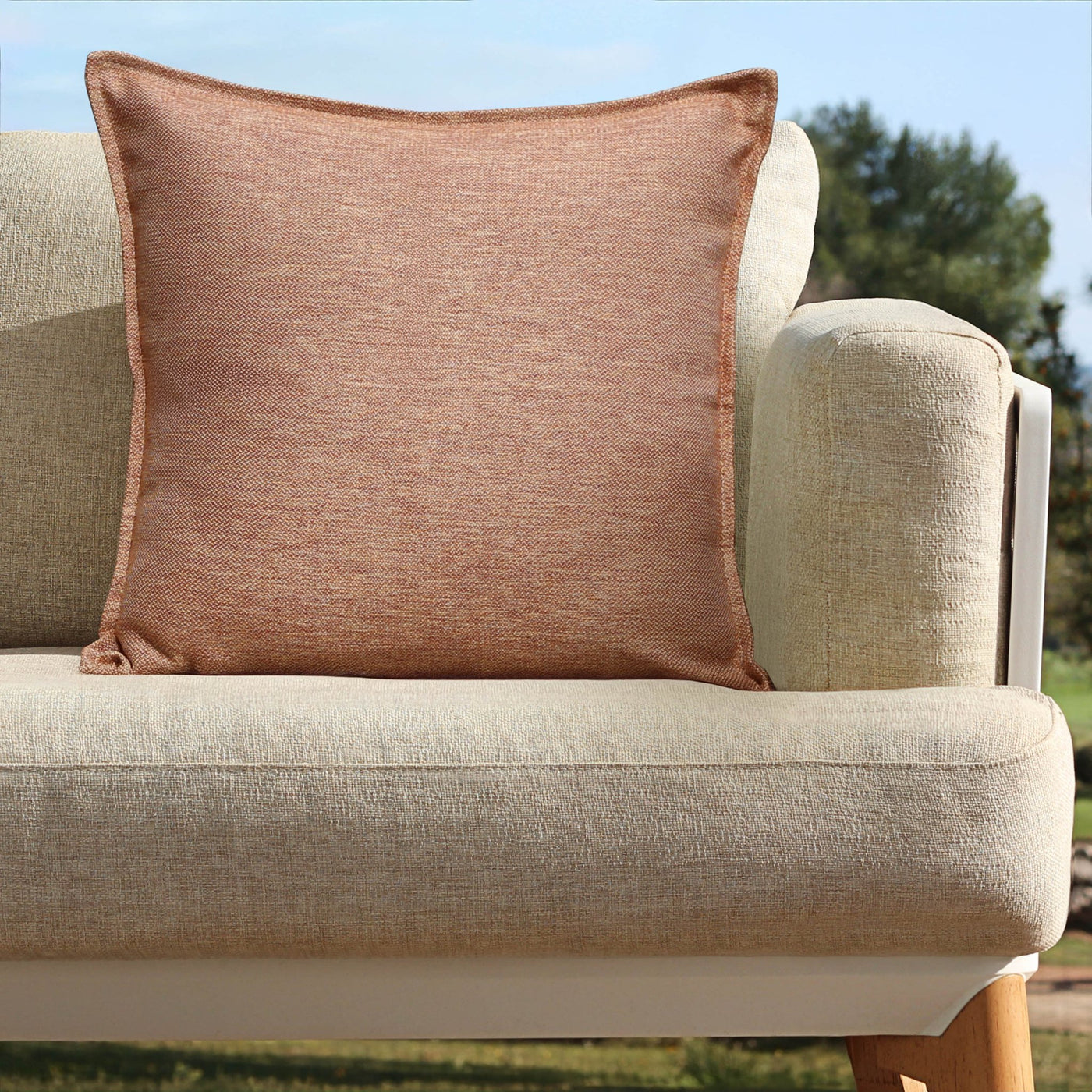Coussin déco d'extérieur Kalena en terracotta de 60x60 cm de Meublot, avec tissu résistant pour mobilier extérieur.