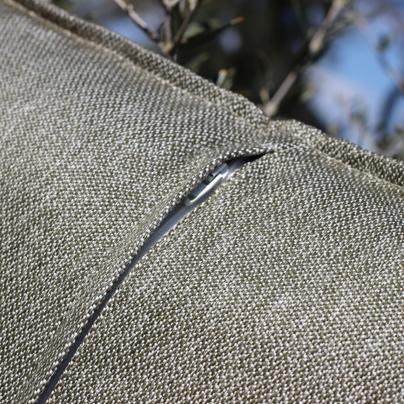 Coussin déco d'extérieur vert olive Kalena de 60x60 cm de Meublot, avec fermeture éclair et tissu résistant aux intempéries.