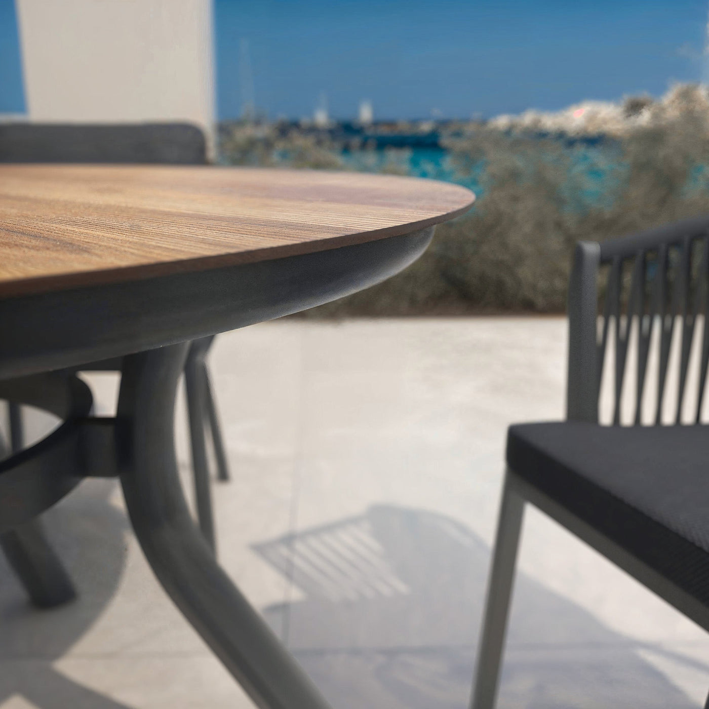 Table de jardin ronde Meublot Amalfi pour 5 personnes, plateau gris avec ambiance chaleureuse, diamètre de 120 cm.